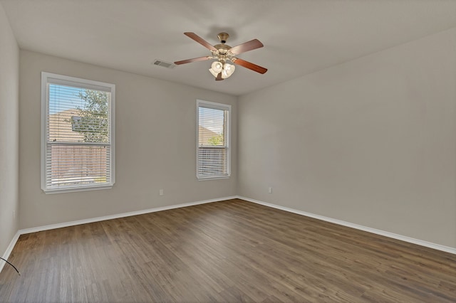 unfurnished room with a healthy amount of sunlight, dark wood-type flooring, and ceiling fan