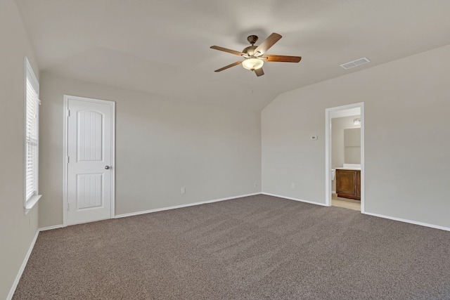 unfurnished bedroom featuring a closet, lofted ceiling, connected bathroom, carpet, and ceiling fan