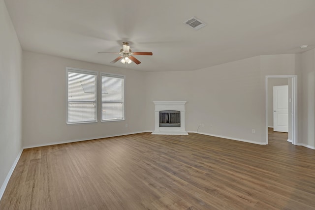 unfurnished living room with ceiling fan, hardwood / wood-style flooring, and a brick fireplace