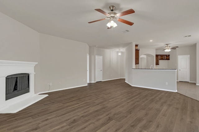 unfurnished living room featuring dark hardwood / wood-style flooring and ceiling fan