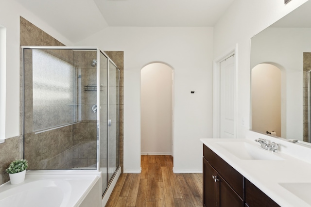 bathroom featuring vanity, hardwood / wood-style floors, plus walk in shower, and vaulted ceiling