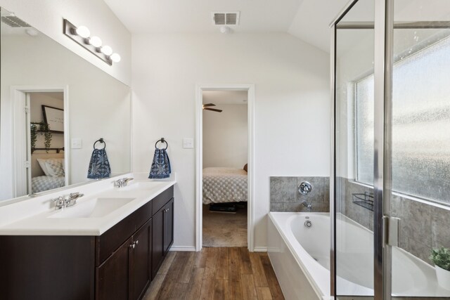 bathroom with vanity, vaulted ceiling, shower with separate bathtub, and wood-type flooring