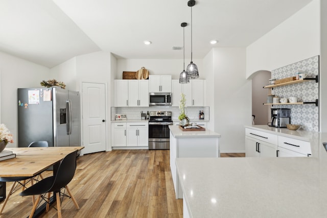 kitchen with white cabinetry, stainless steel appliances, light hardwood / wood-style flooring, and hanging light fixtures