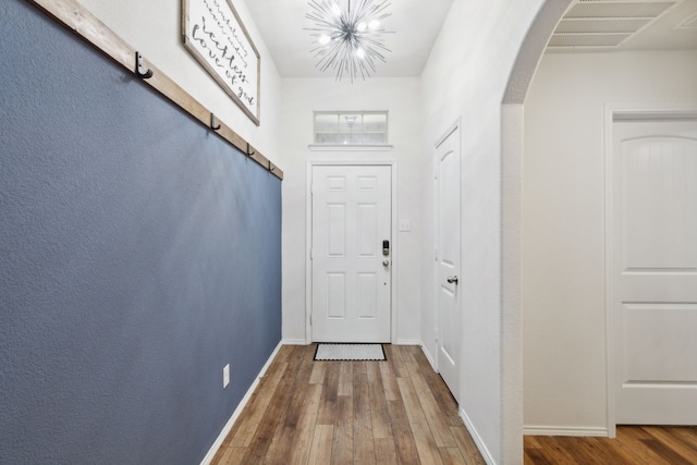 doorway with hardwood / wood-style floors and a notable chandelier