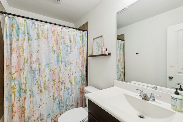 bathroom with vanity, toilet, walk in shower, and a textured ceiling