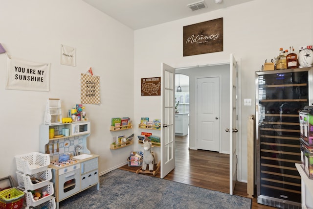 game room with dark wood-type flooring and wine cooler