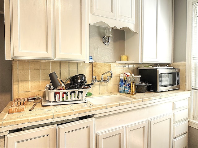 kitchen featuring tile countertops, sink, and decorative backsplash