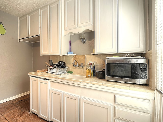 kitchen with sink, a textured ceiling, tile counters, and tasteful backsplash