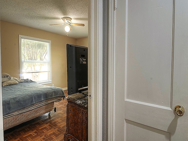 bedroom featuring a textured ceiling, ceiling fan, and dark parquet flooring