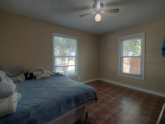 bedroom featuring a textured ceiling, ceiling fan, and dark parquet flooring