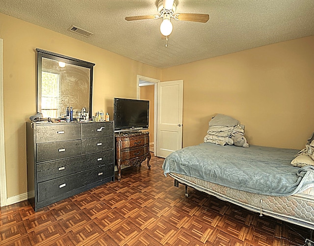 bedroom featuring ceiling fan, a textured ceiling, and dark parquet floors