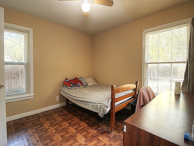 bedroom with ceiling fan, a textured ceiling, and dark parquet floors