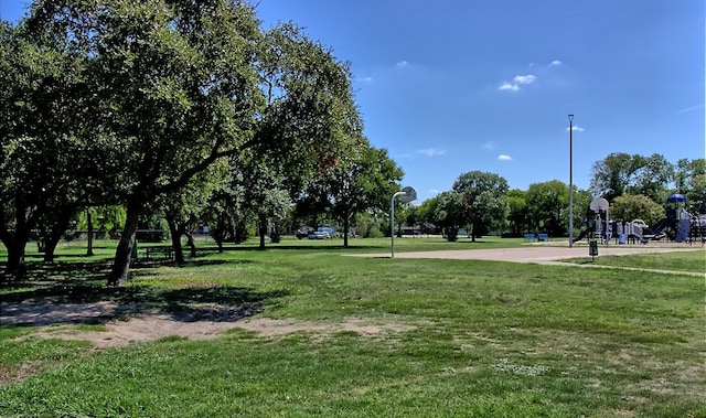 view of home's community featuring a playground, basketball hoop, and a yard