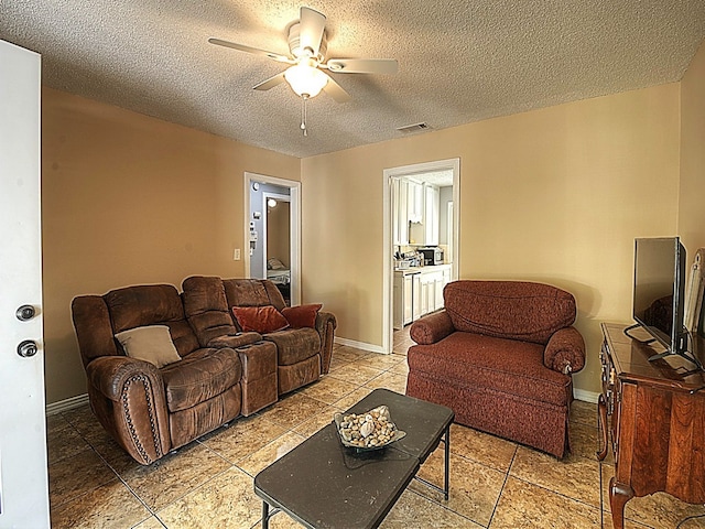 living room with a textured ceiling and ceiling fan