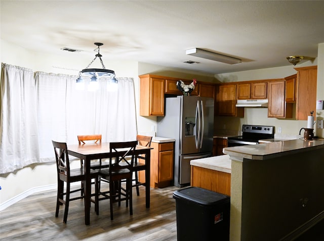 kitchen with pendant lighting, kitchen peninsula, appliances with stainless steel finishes, and dark hardwood / wood-style flooring