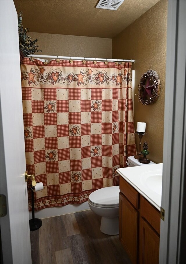 bathroom with vanity, toilet, a textured ceiling, a shower with curtain, and hardwood / wood-style floors