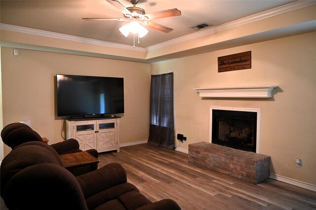 living room featuring ornamental molding, a brick fireplace, ceiling fan, and hardwood / wood-style flooring