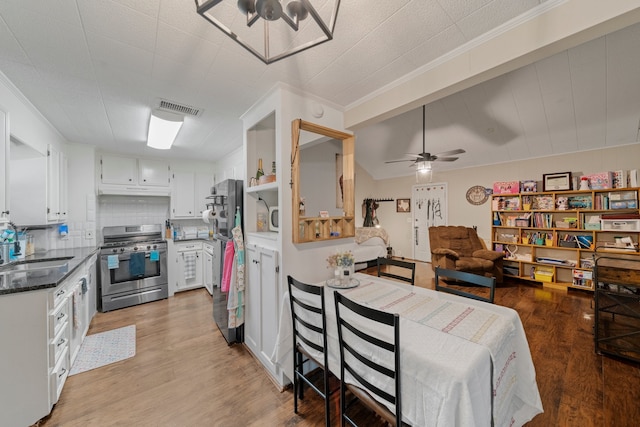 kitchen with light hardwood / wood-style floors, sink, white cabinetry, decorative backsplash, and stainless steel appliances