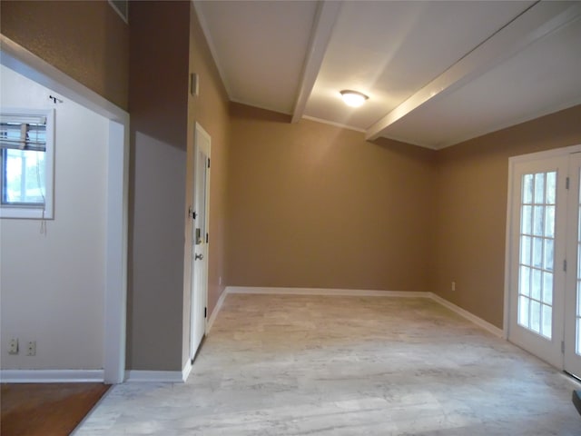 empty room featuring french doors, a healthy amount of sunlight, and beamed ceiling