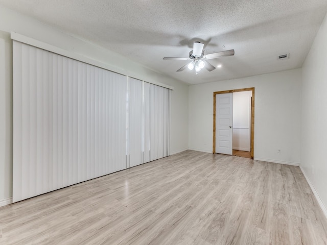 spare room featuring light wood-type flooring, ceiling fan, and a textured ceiling