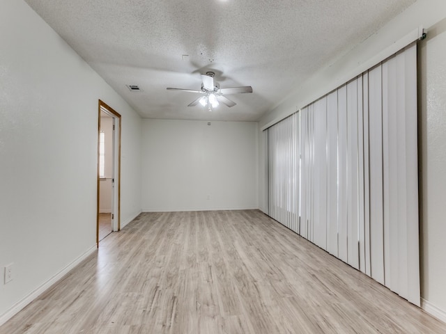 spare room with light hardwood / wood-style floors, ceiling fan, and a textured ceiling