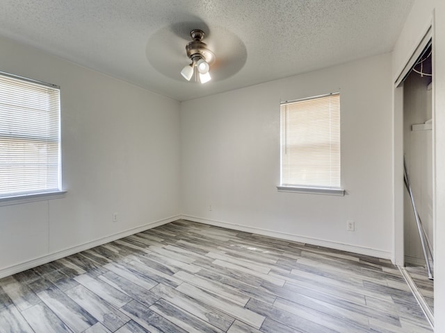 unfurnished bedroom featuring multiple windows, a textured ceiling, ceiling fan, and a closet