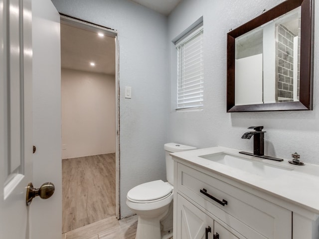 bathroom featuring toilet, vanity, and hardwood / wood-style floors