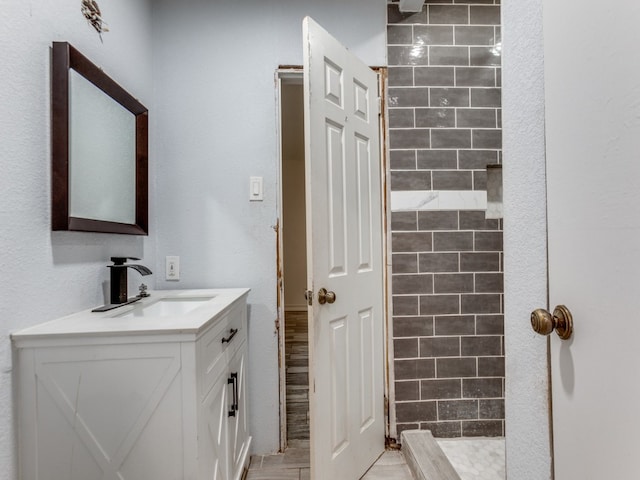 bathroom featuring tile walls, walk in shower, and vanity