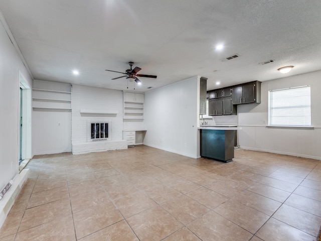 unfurnished living room featuring ceiling fan, a textured ceiling, a fireplace, and light tile patterned flooring