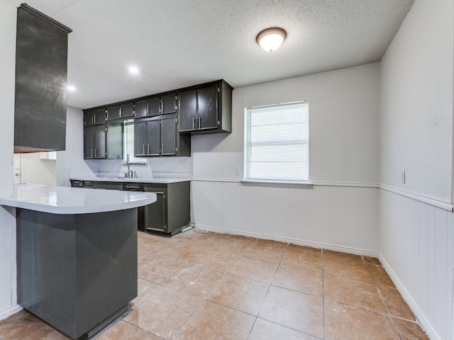 kitchen with light tile patterned floors, sink, kitchen peninsula, a textured ceiling, and a breakfast bar area