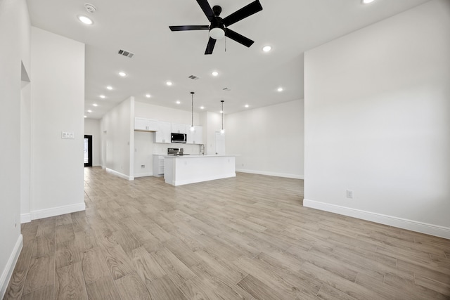 unfurnished living room with visible vents, a ceiling fan, recessed lighting, light wood finished floors, and baseboards