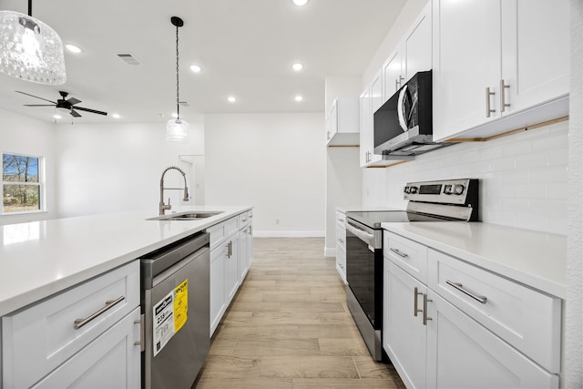 kitchen with visible vents, a sink, backsplash, appliances with stainless steel finishes, and white cabinets