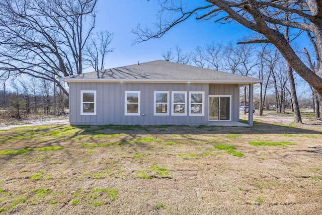 rear view of property with board and batten siding and roof with shingles