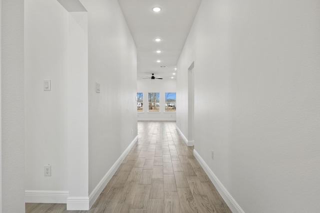 corridor with recessed lighting, baseboards, and light wood finished floors