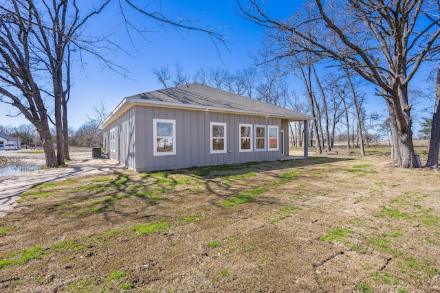 view of side of home with central air condition unit and roof with shingles