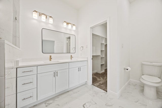 bathroom with double vanity, marble finish floor, toilet, and a sink