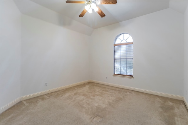 spare room with ceiling fan, light colored carpet, and vaulted ceiling