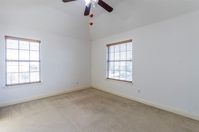 carpeted spare room featuring ceiling fan, vaulted ceiling, and a healthy amount of sunlight