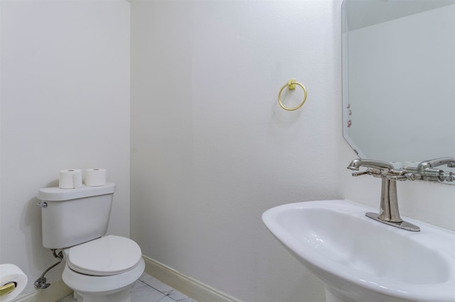 bathroom with toilet, sink, and tile patterned floors