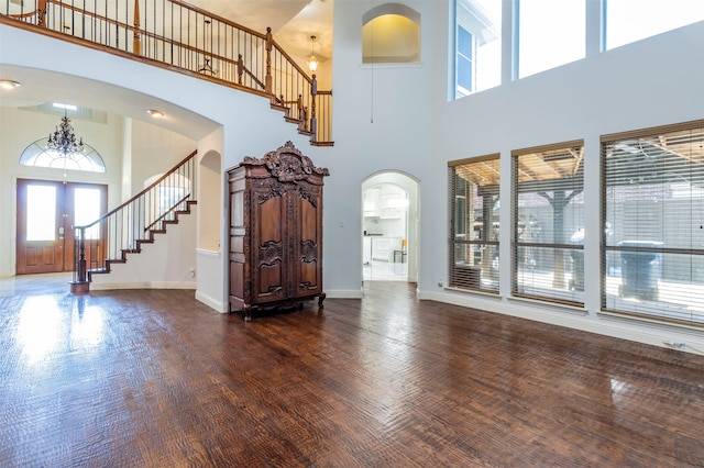 unfurnished living room with dark hardwood / wood-style floors, an inviting chandelier, and a towering ceiling