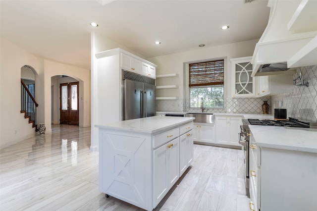 kitchen with decorative backsplash, white cabinets, a kitchen island, custom exhaust hood, and high quality appliances