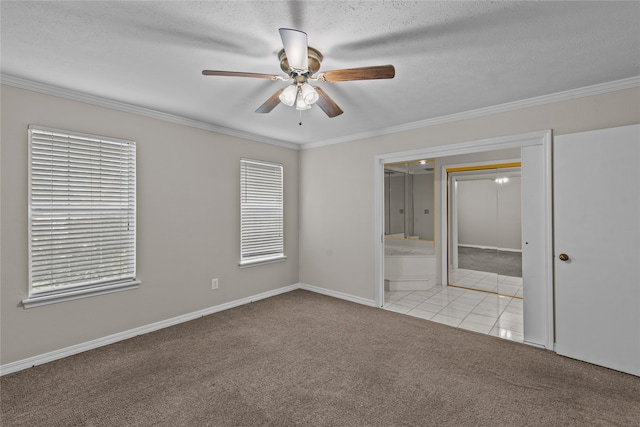 spare room with ceiling fan, light colored carpet, crown molding, and a textured ceiling