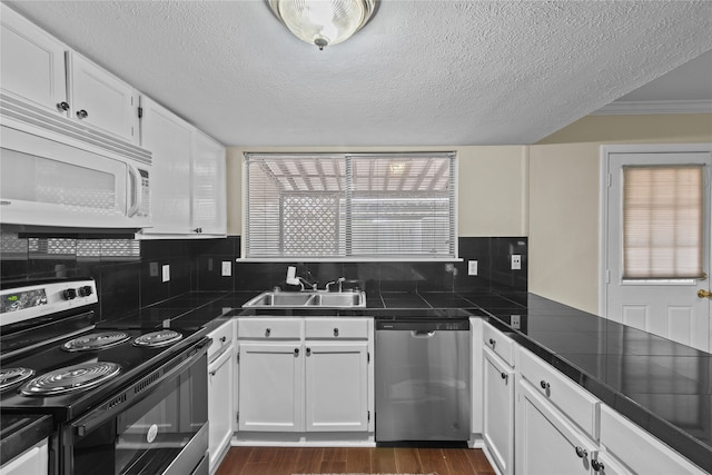 kitchen featuring dark hardwood / wood-style floors, tasteful backsplash, sink, white cabinets, and stainless steel appliances