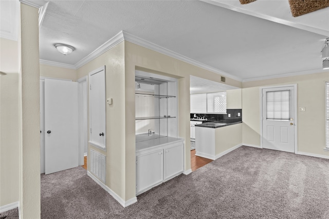 hallway featuring a textured ceiling, crown molding, and dark carpet