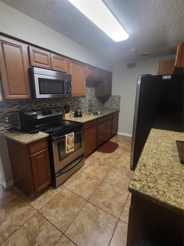 kitchen featuring light tile patterned flooring, sink, tasteful backsplash, a textured ceiling, and appliances with stainless steel finishes