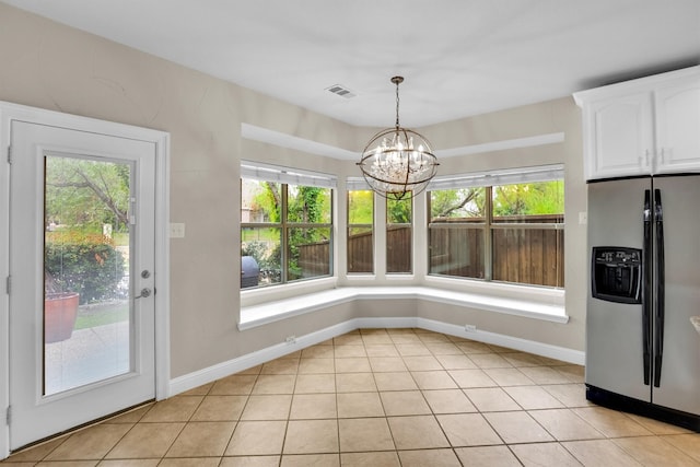 unfurnished dining area with an inviting chandelier, light tile patterned floors, and a wealth of natural light