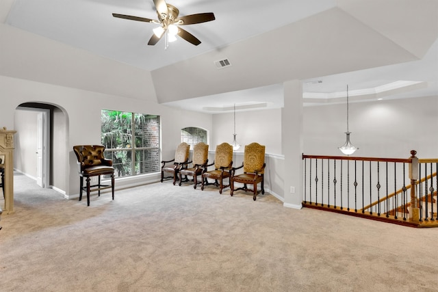 sitting room featuring ceiling fan with notable chandelier, carpet, and a raised ceiling