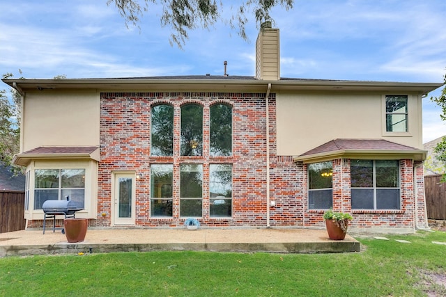 back of property with a lawn and a patio