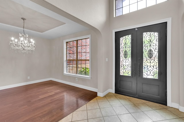 entryway featuring light wood-type flooring, a chandelier, and french doors