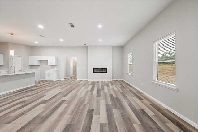 unfurnished living room featuring light wood-type flooring and sink